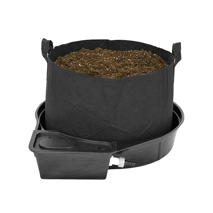 A black fabric pot with a raised base and channels designed for hydroponic gardening, showing the MegaValve and a half-inch white reflective pipe.